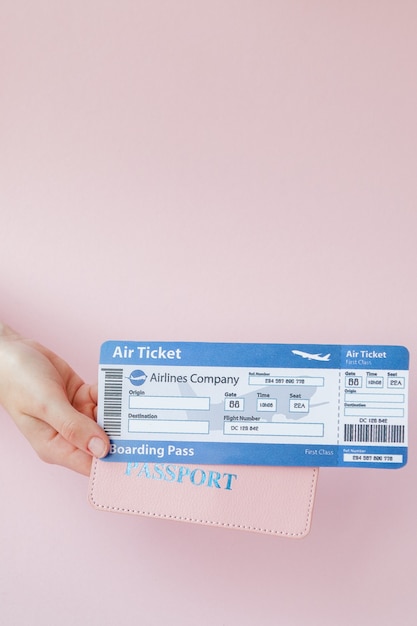 Close up horizontal féminin touristique en main billets d'avion avec passeport orange, carte d'embarquement sur rose