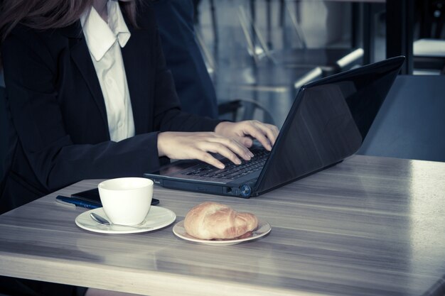 Close-up jeune femme d&#39;affaires travaillant sur l&#39;ordinateur au café