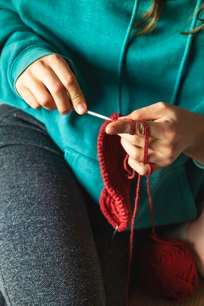 Photo close-up d'une jeune femme blanche 39s mains tricotant un foulard assise sur le canapé dans le salon