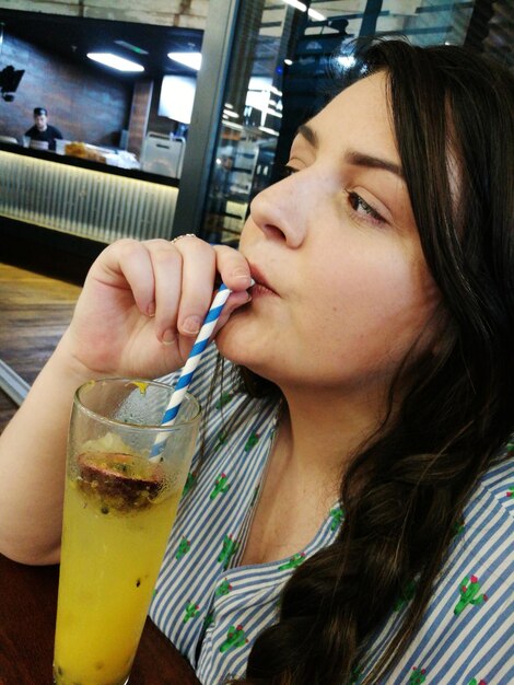 Close-up d'une jeune femme buvant un cocktail dans un café