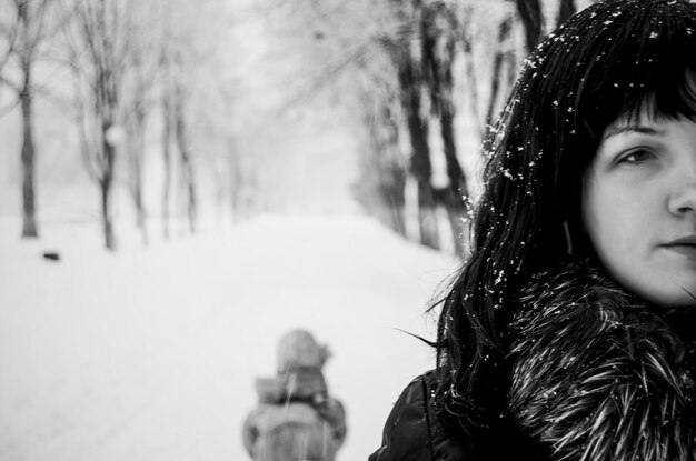 Photo close-up d'une jeune femme debout sur une rue couverte de neige