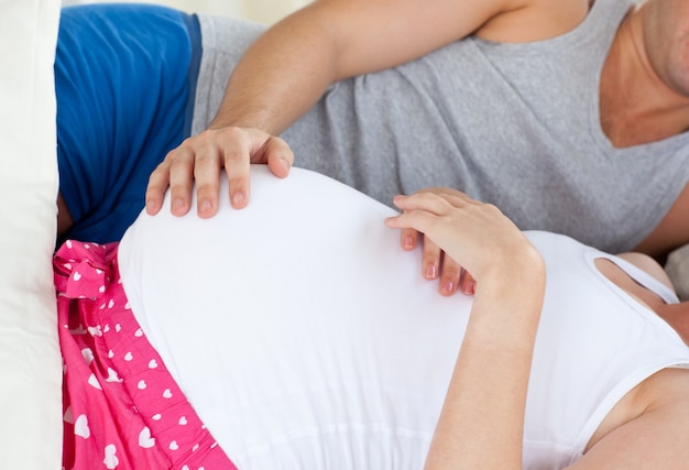 Photo close-up d'une jeune femme enceinte allongée sur le lit avec son mari