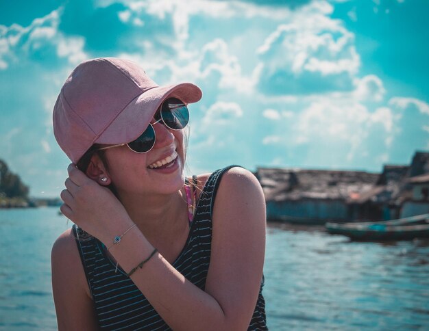 Close-up d'une jeune femme joyeuse assise au bord de la mer