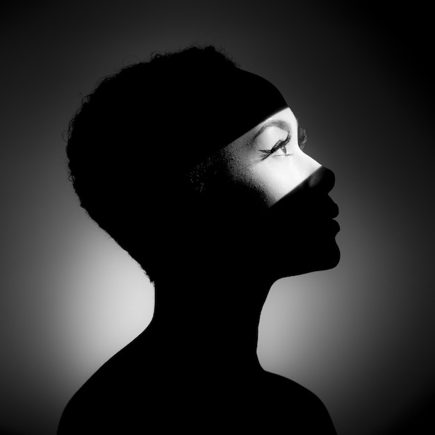 Close-up d'une jeune femme à la lumière sur un fond noir