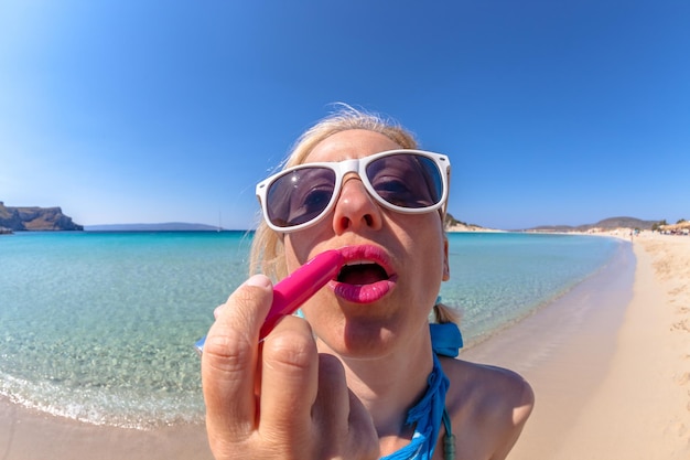 Photo close-up d'une jeune femme portant des lunettes de soleil sur la plage contre un ciel bleu clair