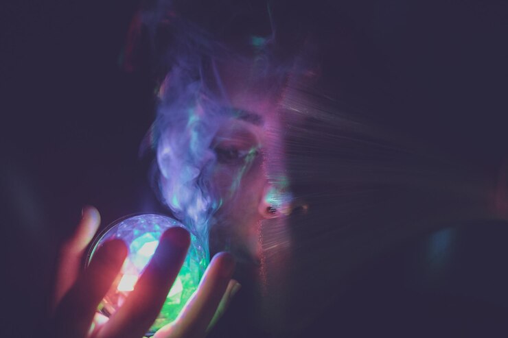 Photo close-up d'une jeune femme tenant une boule de cristal sur un fond noir
