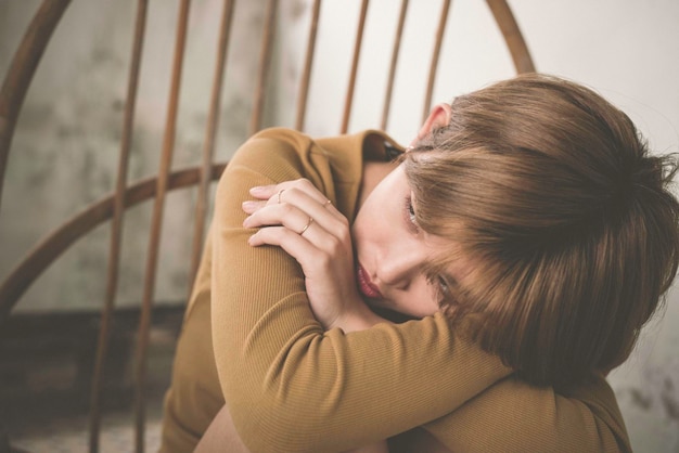 Photo close-up d'une jeune femme triste assise sur une chaise dans une pièce