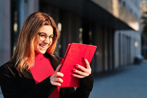 Close-up d'une jeune femme utilisant une tablette numérique alors qu'elle se tient dans la rue du district de la ville financière Concept urbain et technologique