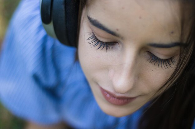 Photo close-up d'une jeune femme avec les yeux fermés écoutant de la musique