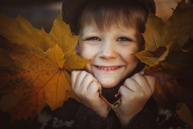 Photo close-up d'un jeune garçon tenant des feuilles d'automne