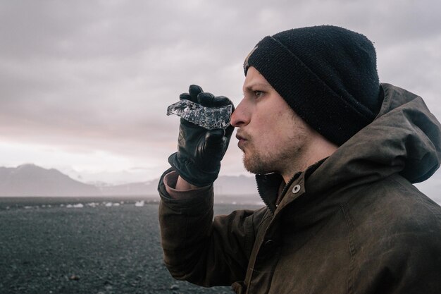 Photo close-up d'un jeune homme tenant de la glace et détournant le regard vers le ciel