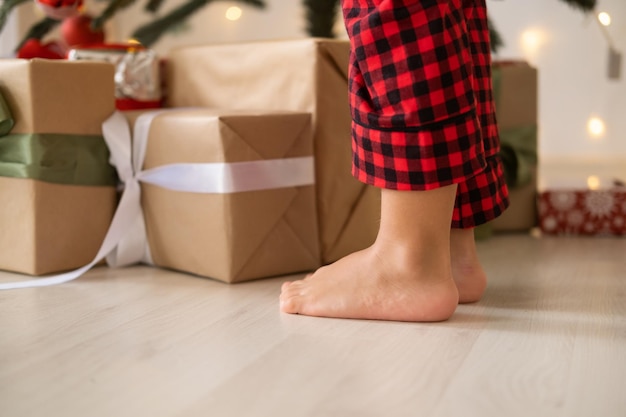 Close up kid jambes en pyjama de Noël rouge près de coffrets cadeaux