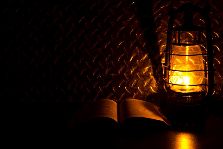 Photo close-up d'une lanterne éclairée par un livre ouvert sur une table dans une chambre noire