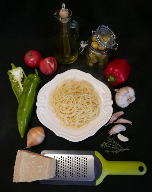 Close-up de légumes et de râpe avec des spaghettis sur fond noir