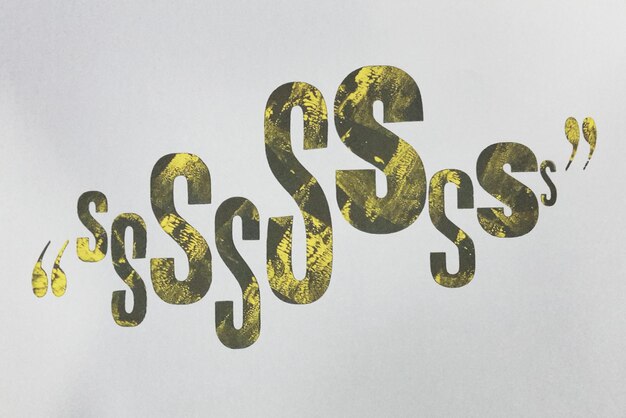 Photo close-up de la lettre jaune s avec apostrophe sur fond blanc