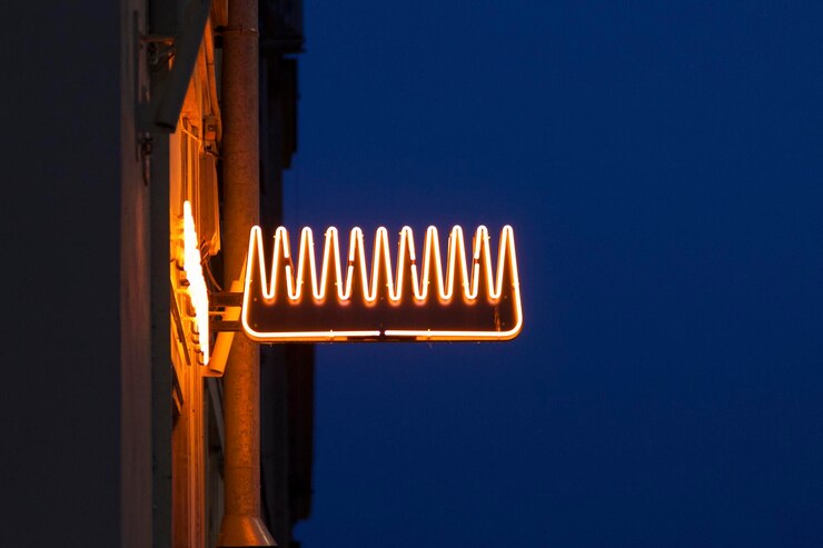 Photo close-up sur une lumière au néon en forme de peigne au-dessus d'une coiffeuse