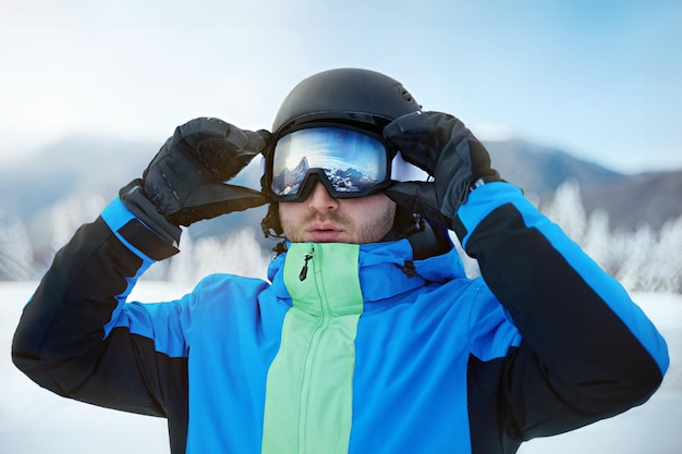 Close up des lunettes de ski d'un homme avec le reflet de montagnes enneigées Une chaîne de montagnes reflétée dans le masque de ski Portrait d'un homme à la station de ski sur le fond des montagnes et du ciel