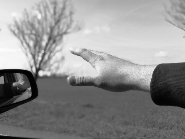 Photo close-up de la main faisant des gestes à travers la fenêtre de la voiture contre le ciel