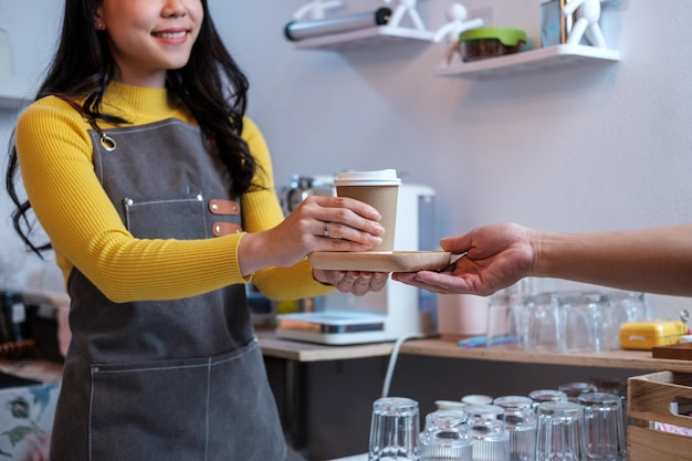 Photo close up main féminine prenant une tasse de café chaud du barista dans le magasin de confiserie