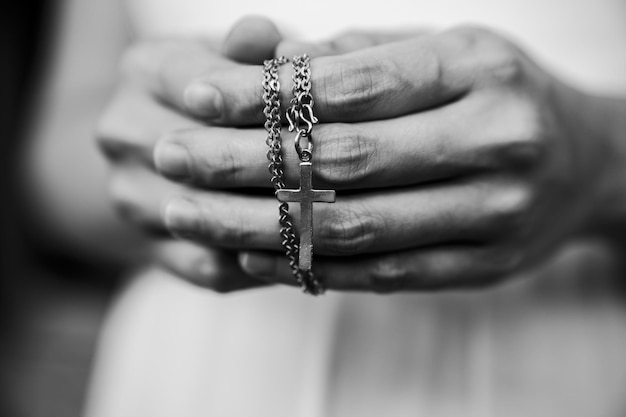 Photo close-up de la main d'une femme tenant une croix sur un fond flou