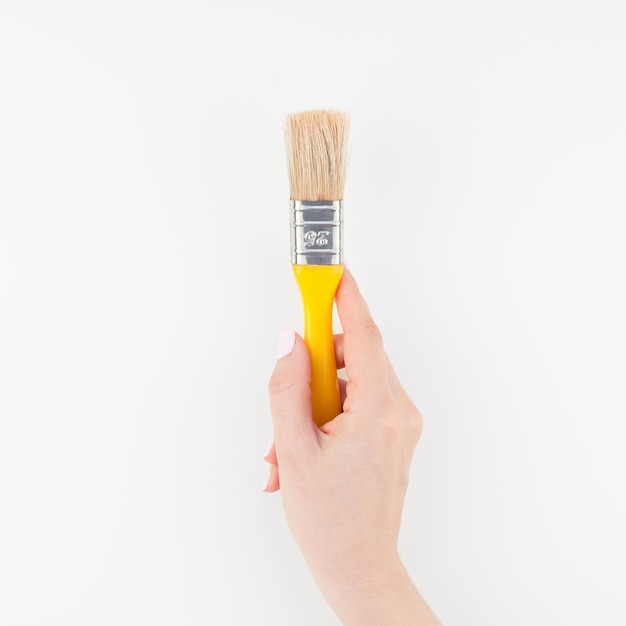 Close-up de la main d'une femme tenant un pinceau sur fond blanc