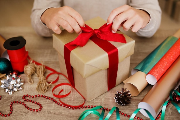 Photo close up de la main de l'homme attachant un arc sur le cadeau à la table