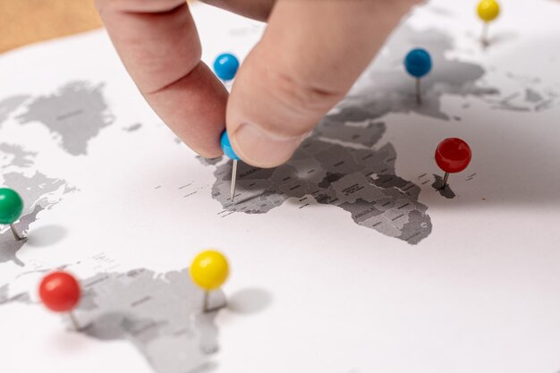 Photo close-up de la main humaine épinglée sur la carte du monde concept de destination de voyage