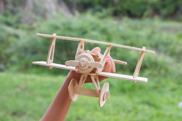 Photo close-up d'une main tenant un avion jouet en bois