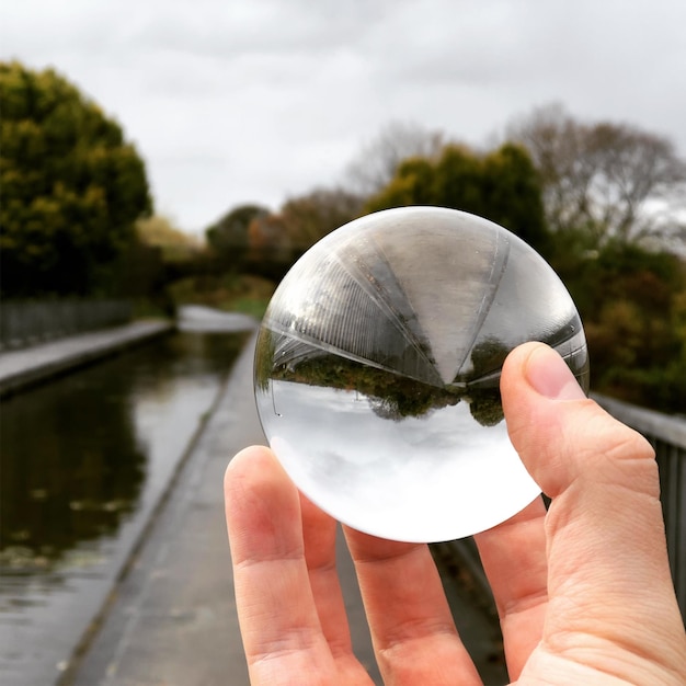 Close-up de la main tenant une boule de cristal contre le verre