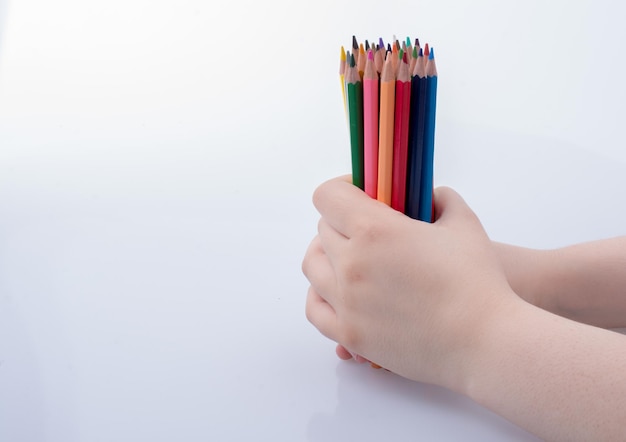 Photo close-up d'une main tenant des crayons de couleur sur un fond blanc