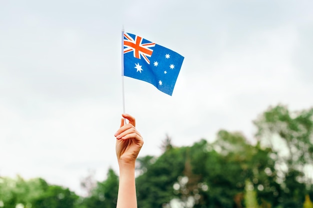 Close-up de la main tenant le drapeau australien contre le ciel bleu célébration de la fête de l'Australie en janvier