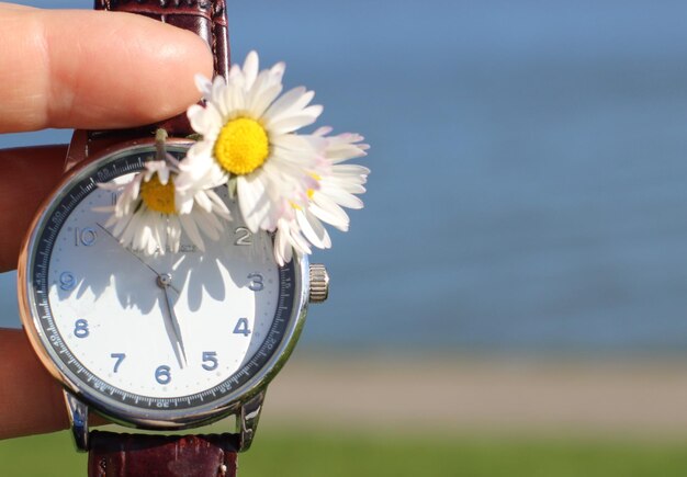 Photo close-up d'une main tenant une fleur et une montre de poignet