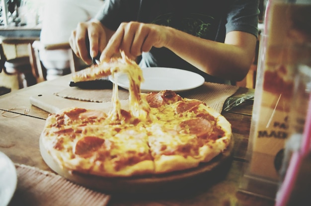 Photo close-up d'une main tenant une pizza dans une assiette