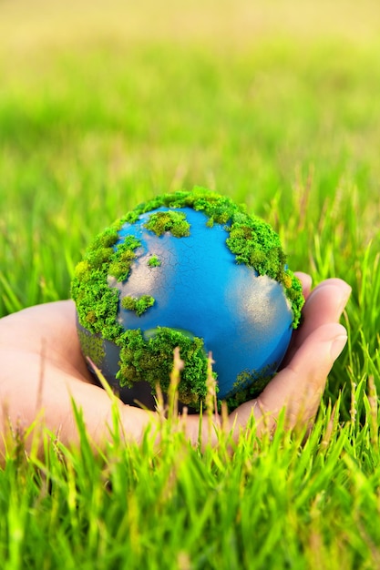 Close-up d'une main tenant la planète Terre artificielle sur l'herbe