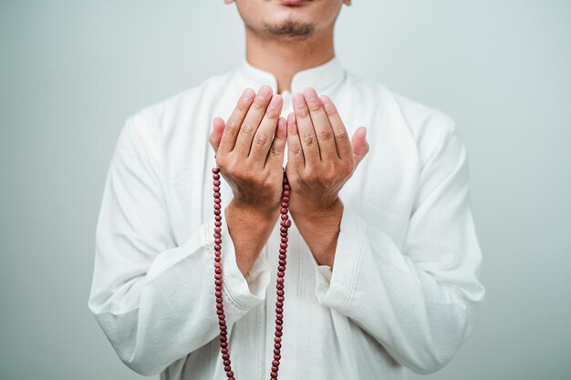 Close up Main tenant un tasbih ou un chapelet sur fond blanc