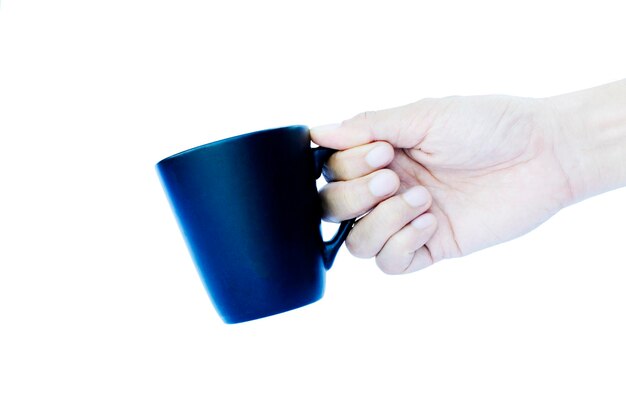 Photo close-up d'une main tenant une tasse de café bleue sur un fond blanc