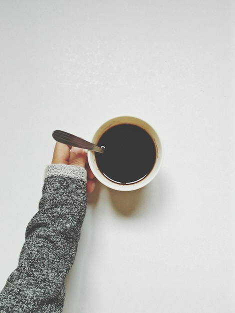 Close-up de la main tenant une tasse de café contre la table