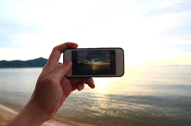 Photo close-up de la main tenant un téléphone portable sur la plage