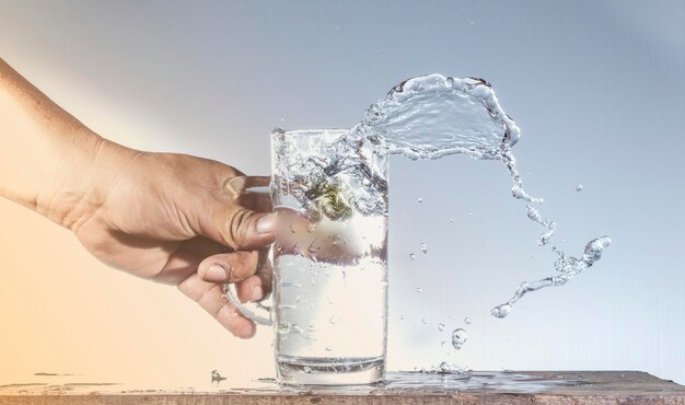 Close-up de la main tenant le verre contre l'eau