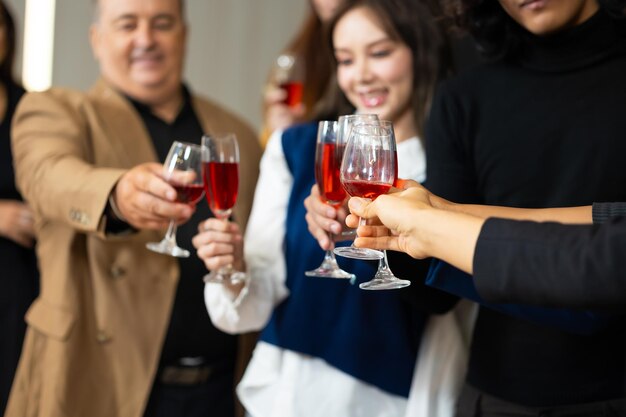 Photo close-up main tenant des verres les gens d'affaires célèbrent en faisant un toast à la fête de l'événement au bureau célébration concept de succès