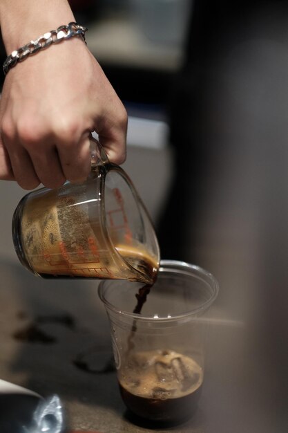 Close-up de la main versant la boisson dans le verre