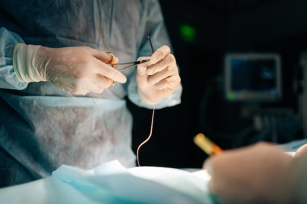 Close-up des mains d'un chirurgien professionnel méconnaissable à l'hôpital faisant une chirurgie invasive