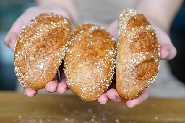 Close-up des mains d'une femme tenant trois morceaux de pain dans les mains en train de faire des sandwichs