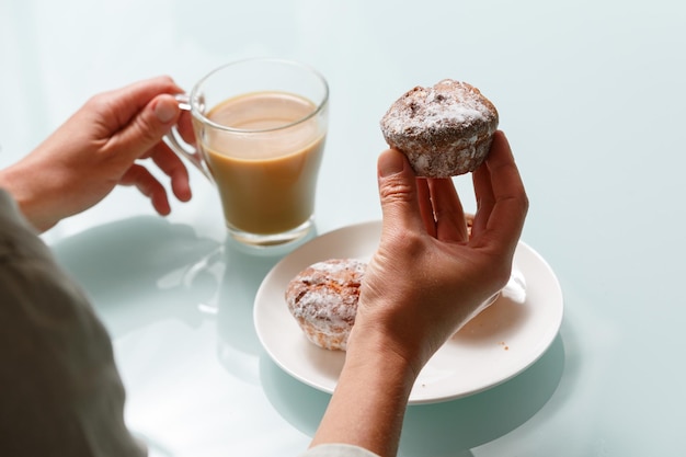 Close up de mains tenant un muffin au caillé et une tasse de café au lait