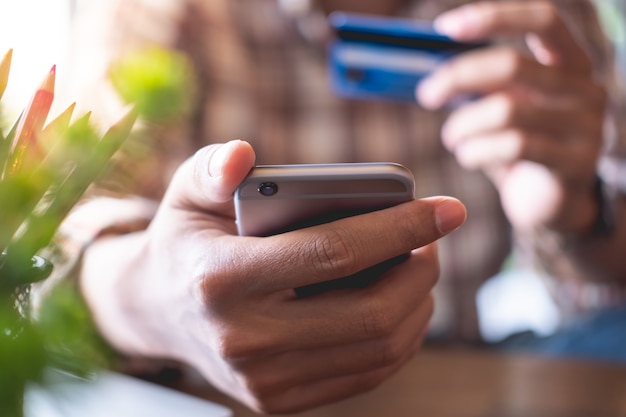 Close up mains tenant un téléphone intelligent pour les achats en ligne avec carte de crédit