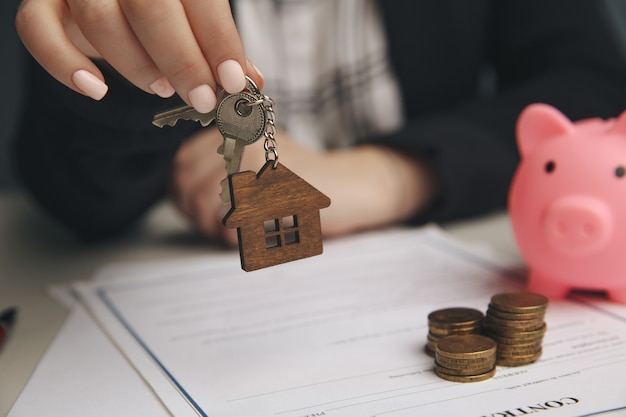 Close up maison jouet en bois avec femme signe un contrat d'achat ou une hypothèque pour une maison