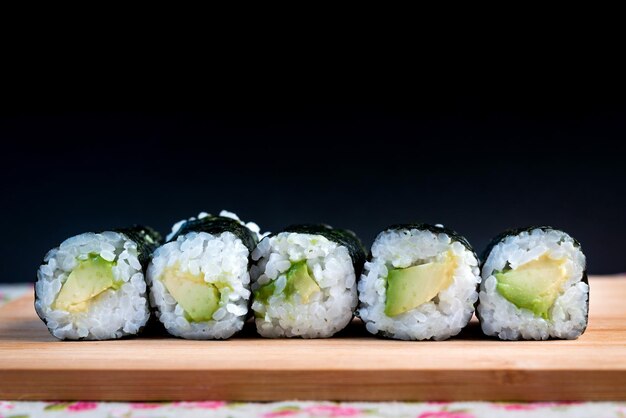 Photo close-up de maki sushi sur une planche à découper sur un fond noir