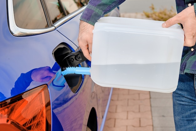 Close up man remplissant un liquide de moteur diesel de la cartouche dans le réservoir de la voiture bleue. Fluide d'échappement diesel pour réduire la pollution de l'air. Solution écologique et écologique.