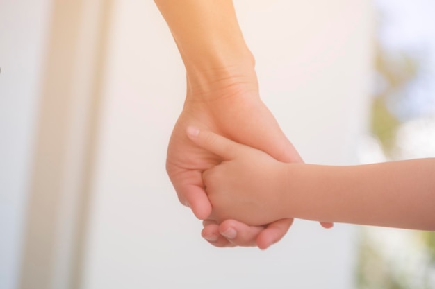 Close-up d'une mère tenant la main de son enfant à la maison