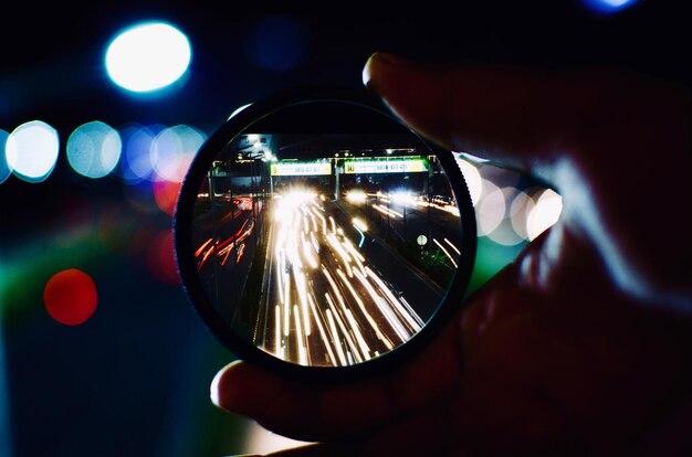 Photo close-up d'un miroir à main avec la réflexion de traces de lumière dans la ville